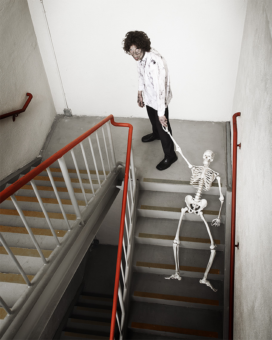 Man dragging a skeleton up a stairway