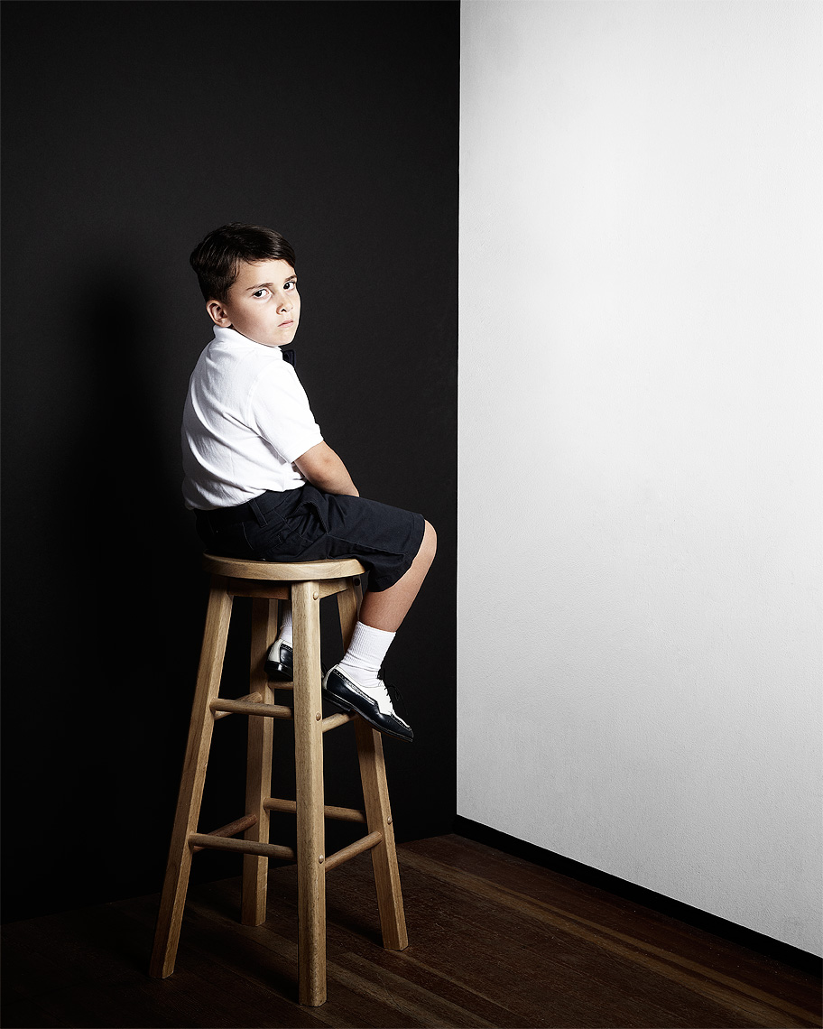 Portrait of an unhappy  kid sitting in a corner corner